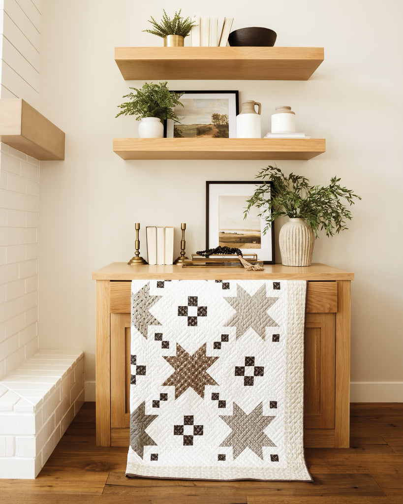 Brown and tan quilt hanging from a wooden hutch 