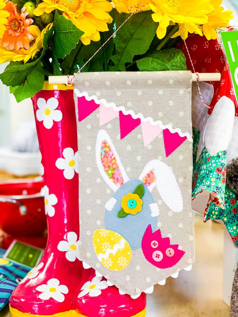 Appliqué bunny hiding behind Easter eggs on a small banner