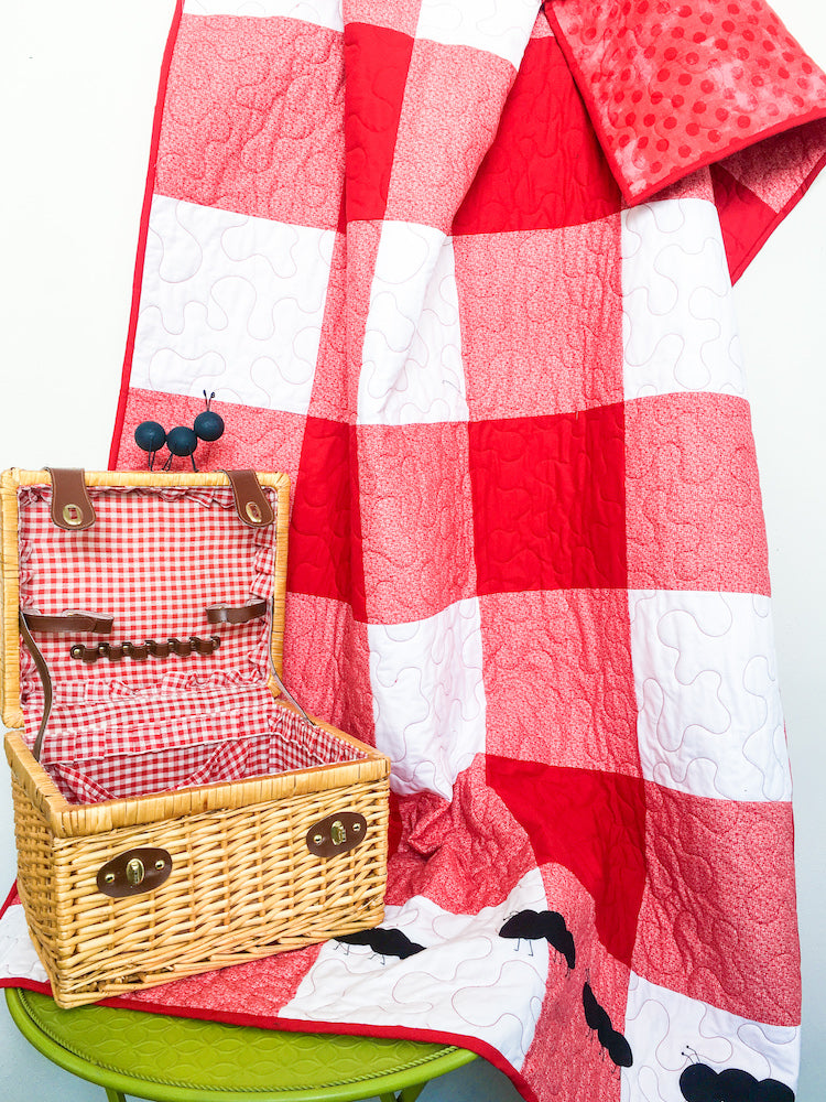 Red Gingham Family Reunion Picnic Quilt beside a picnic basket