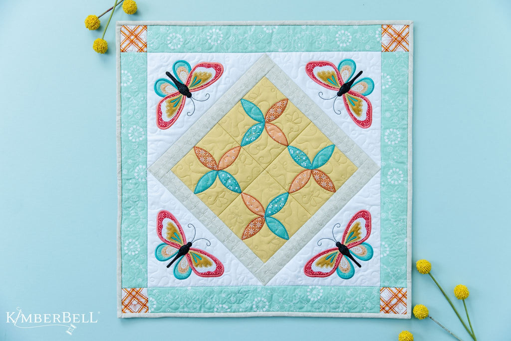 A square table topper with four machine embroidered butterflies. 